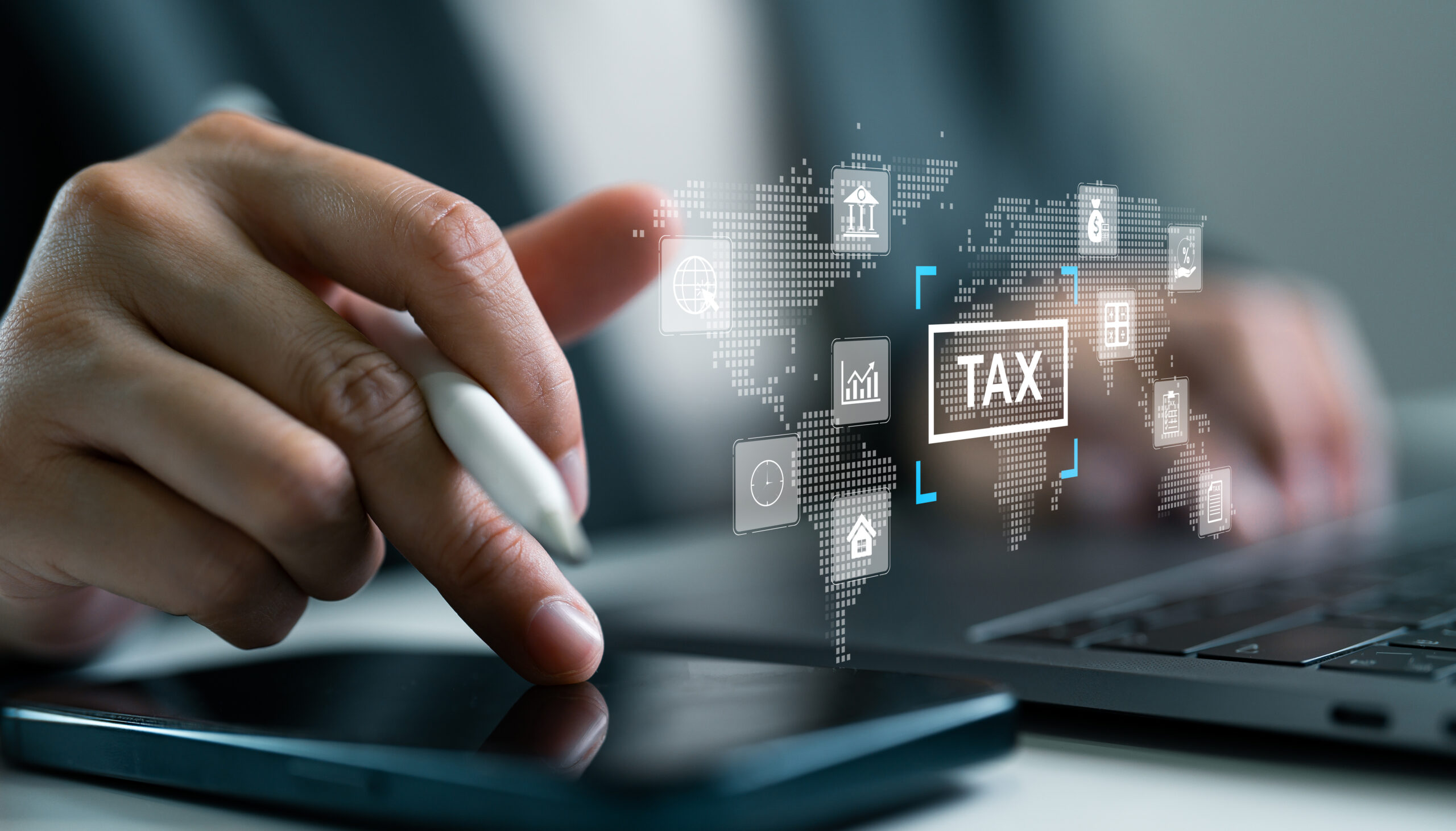 Businessperson using digital smartphone and laptop to manage global tax system. Concept of online tax filing, financial technology, remote accounting software and international taxation management.